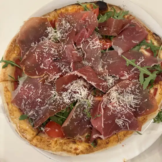 Pizza z szynką parmeńską, rukolą i parmezanem